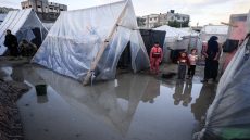 Displaced Palestinians stand amid tents drenched by heavy rain, at a makeshift camp set up by people who fled the ongoing battles between Israel and Hamas militants, in Rafah in the southern Gaza Strip on January 27, 2024. (Photo by AFP)