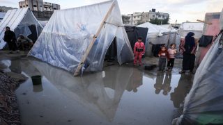 Displaced Palestinians stand amid tents drenched by heavy rain, at a makeshift camp set up by people who fled the ongoing battles between Israel and Hamas militants, in Rafah in the southern Gaza Strip on January 27, 2024. (Photo by AFP)