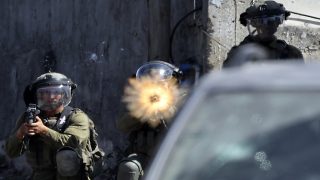 Israeli soldiers take position amid clashes with Palestinian demonstrators following a protest against the expropriation of Palestinian land by Israel in the village of Kfar Qaddum in the occupied West Bank, near the Jewish settlement of Kedumim, on September 30, 2022. (Photo by Jaafar ASHTIYEH / AFP)